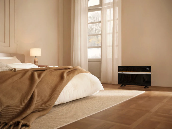In a sunlit bedroom with a plush bed draped in a brown knit throw, a DREO Convection Heater 711 sits elegantly against the wall by the window